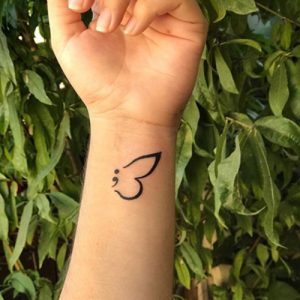 simple butterfly semicolon tattoo on wrist